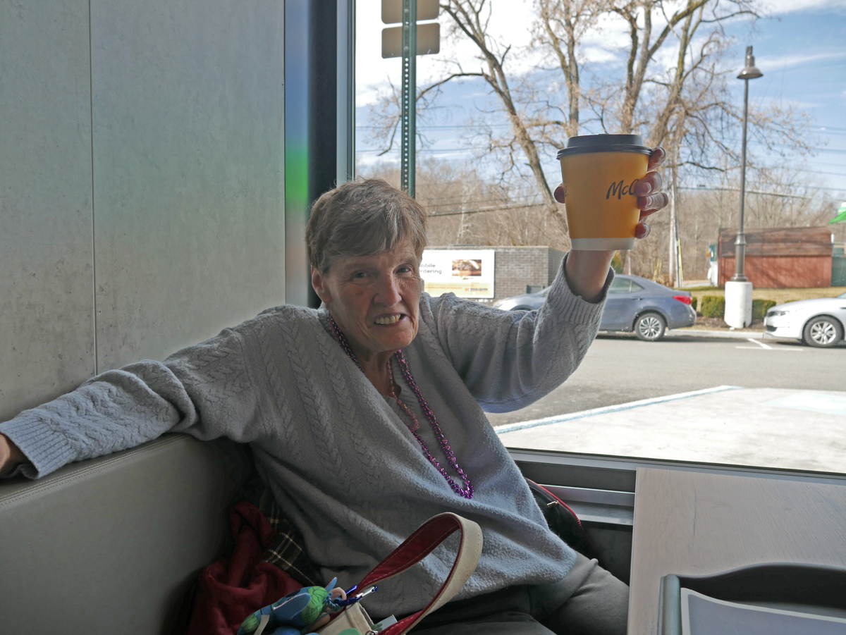 Woman in a restaurant holding up a cup of coffee