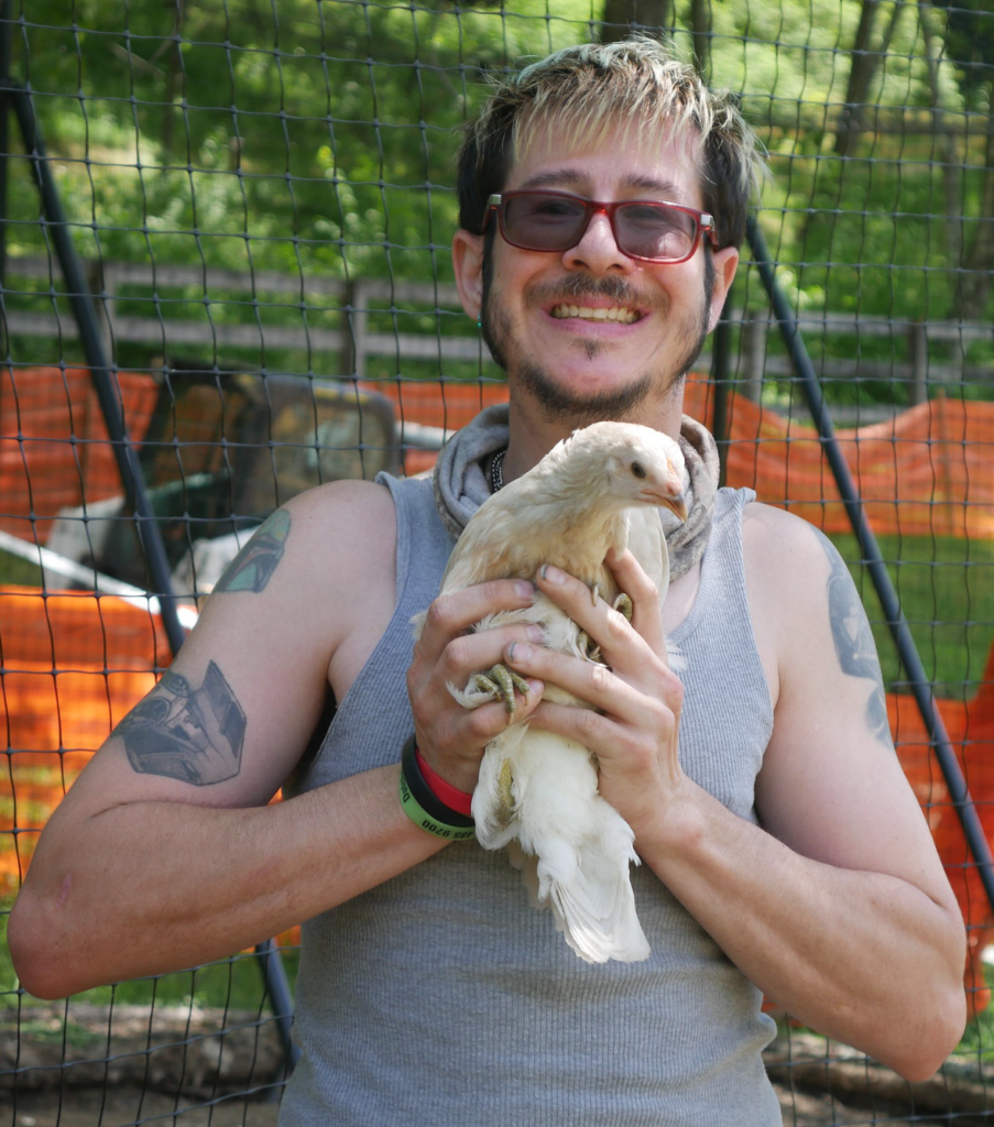 Young man holding a chicken at Cultivating Dreams Farm Respite