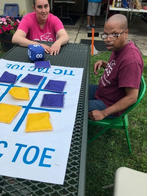 A woman and man living in a Community Based Services residence play a game of tic-tac-toe during a bbq