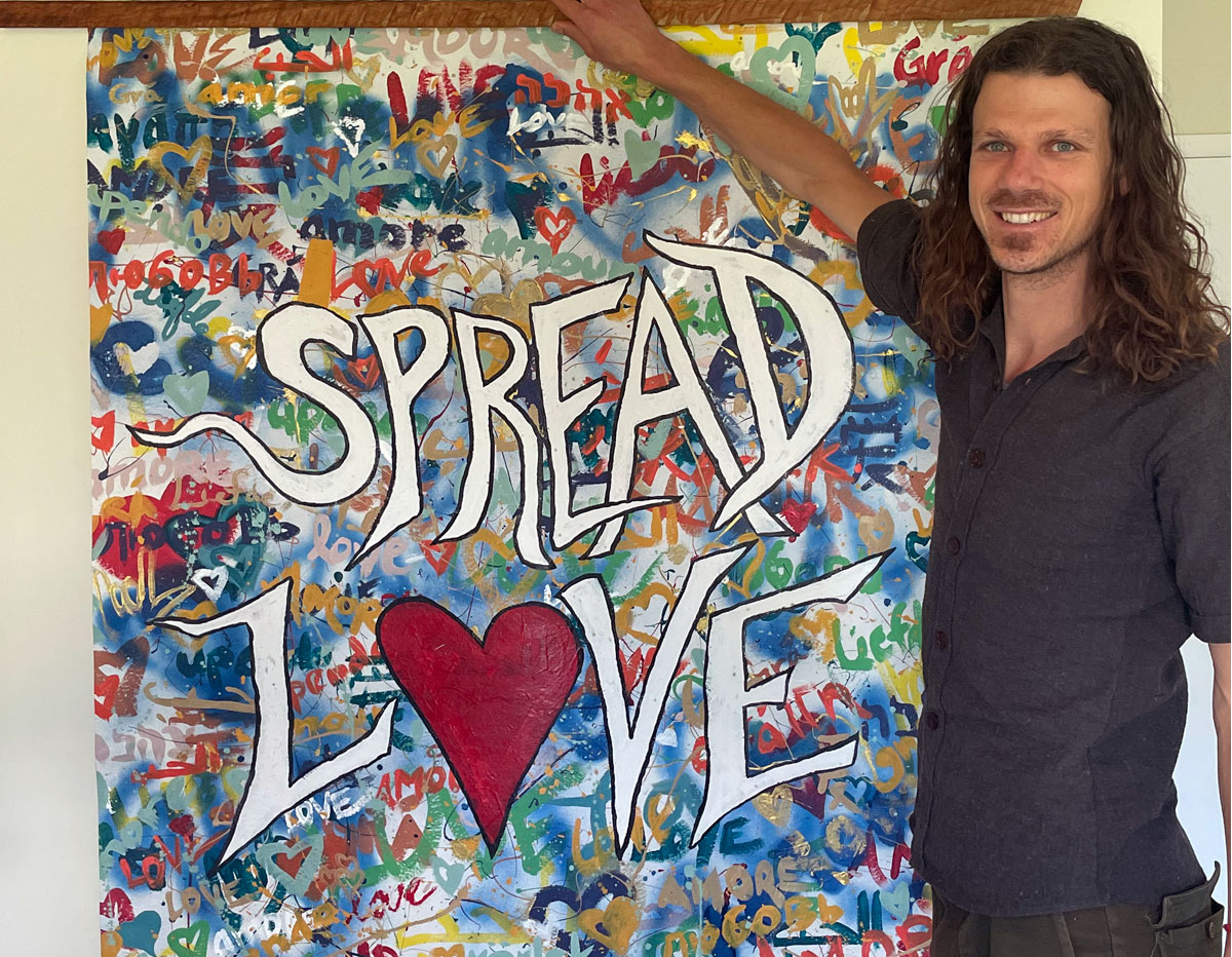 Eric Archer stands in front of his grafitti style painting "Spread Love"
