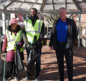A woman and man dressed in safety vests hold garbage bags and stand with their job developer in Peekskill NY where they help clean the streets as part of a job skills program made possible by WIN Waste
