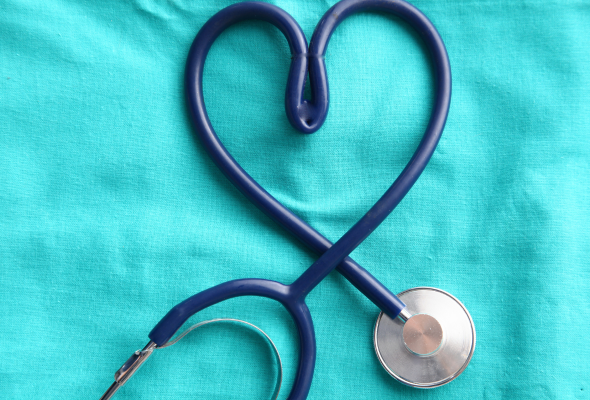 A stethoscope twisted into a heart shape on a greenish blue background
