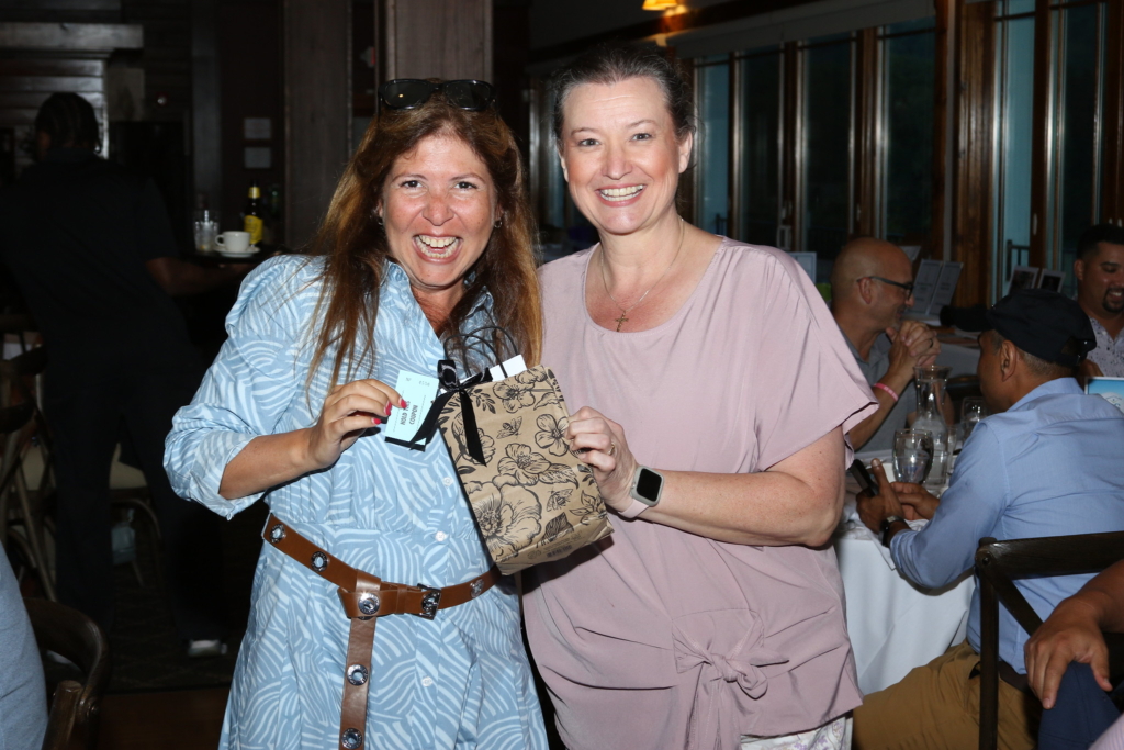 a woman in a blue dress and brown belt accepts her raffle prize of a gift certificate to Angel Face Day Spa