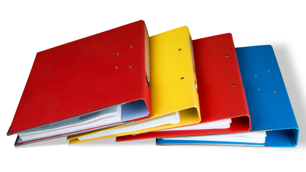 two red, a yellow and blue binders filled with paper lay on a surface