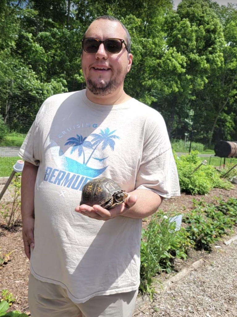 Person with disability holds turtle at Cultivating Dreams Farm, Community Based Service's farm that helps people with disabilities achieve their dreams.