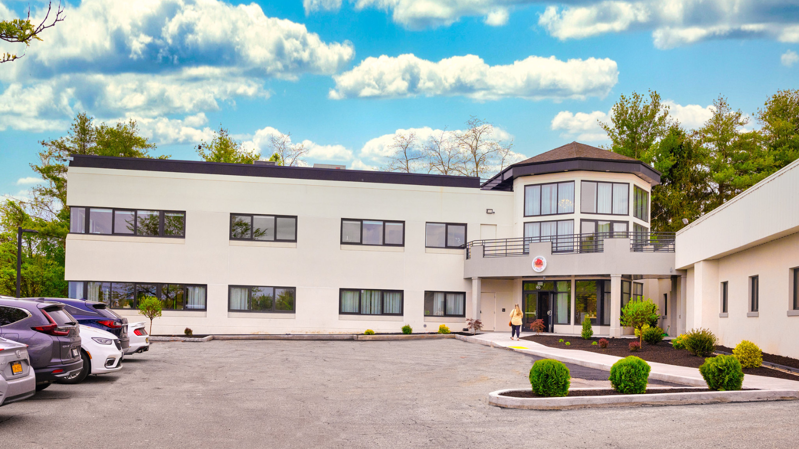 The Hudson Valley InterArts building is a white urban industrial building with black trim set under a blue sky with white clouds.