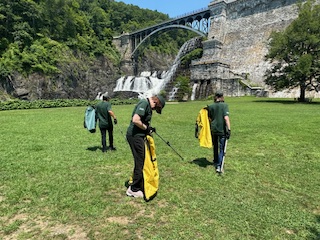 Three workers use garbage pickers to place litter into the sacks they carry at Croton Gorge Park