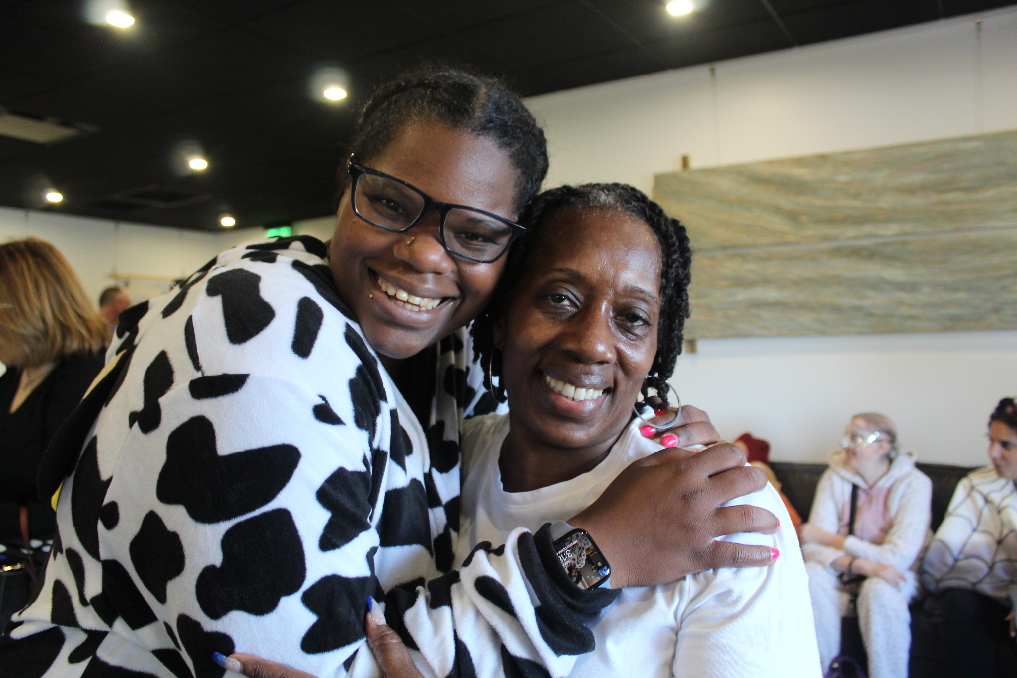 A woman supported by CBS wears a cow costume and stands cheek to cheek with her direct care professional at a Halloween party.