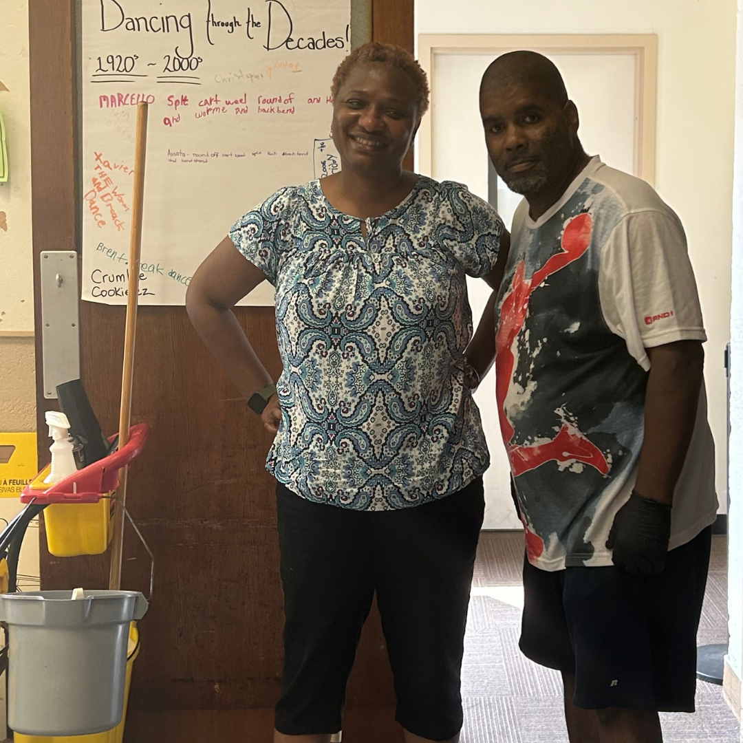 A job coach stands with the person she supports at a job site in a Peekskill school and summer camp.
