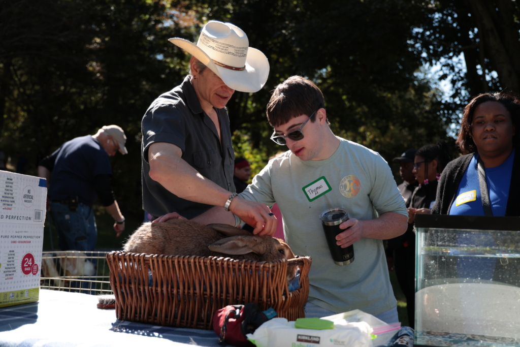 Dallas Fields in a cowboy hat pets a large bunny with a young man in the CBS group day hab