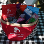 A raffle prize of a basket of assorted Good Reasons dog treats and toys. The basket it wrapped in a Good Reasons bandana.