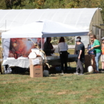 People line up at a tent where they can have apple cider and donuts.