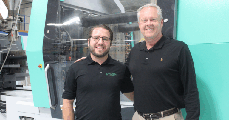 Director of Manufacturing at Vista Labs, Jon Benack stands with Community Relations Manager Joe Conti in front of a plastic molding machine.