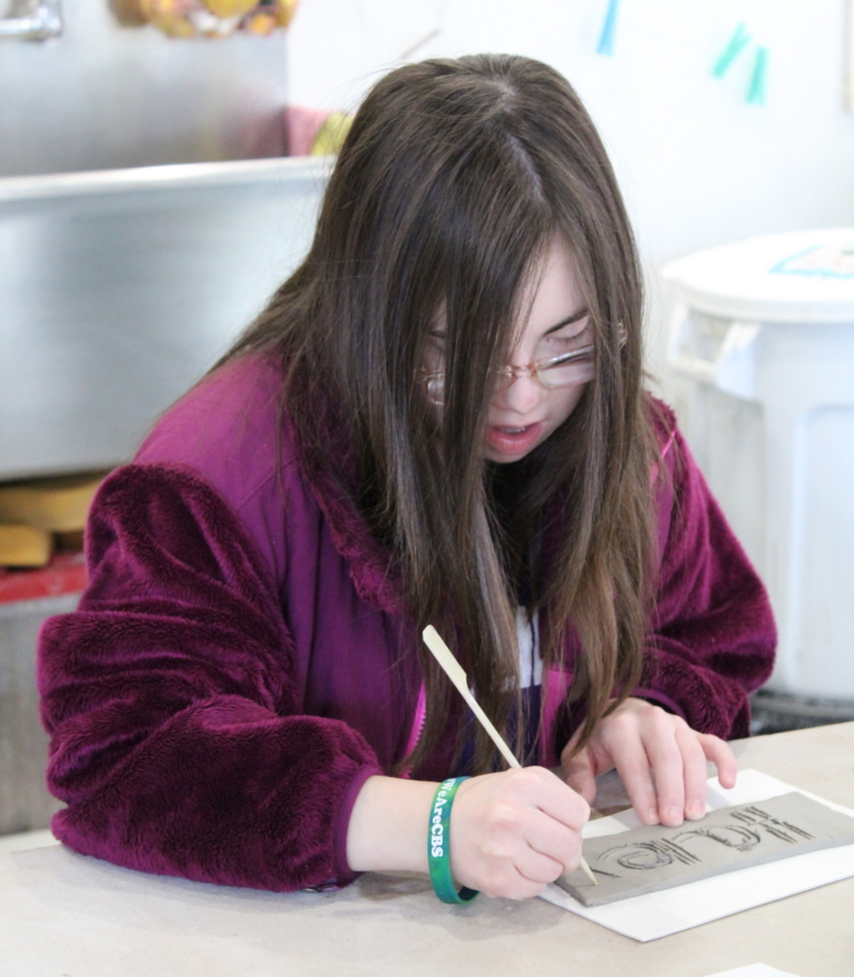 Haley works with a clay slap and glazes at InterArts