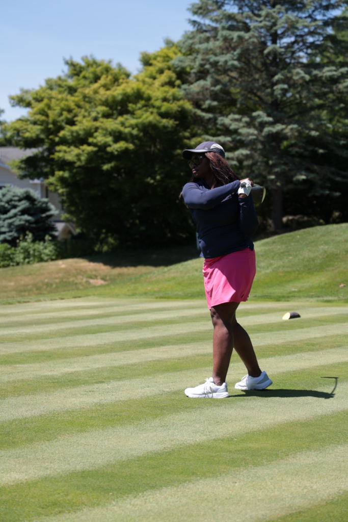 A woman completes her golf swing at the CBS Foundation charity golf scramble on the greens of Salem Golf Club.