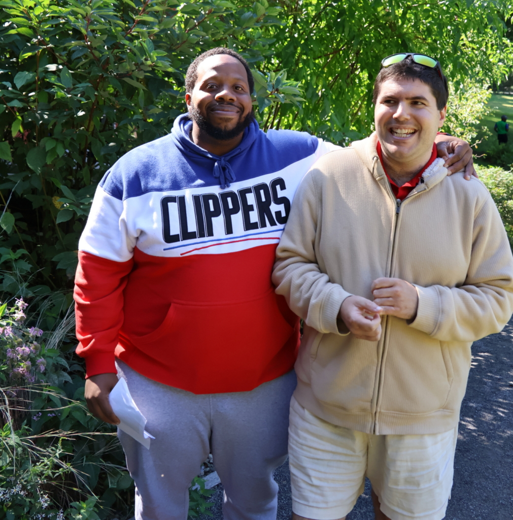 CBS Day Program DSP Chamar Delesline stands with his arm around a person he supports at the Cultivating Dreams Farm.