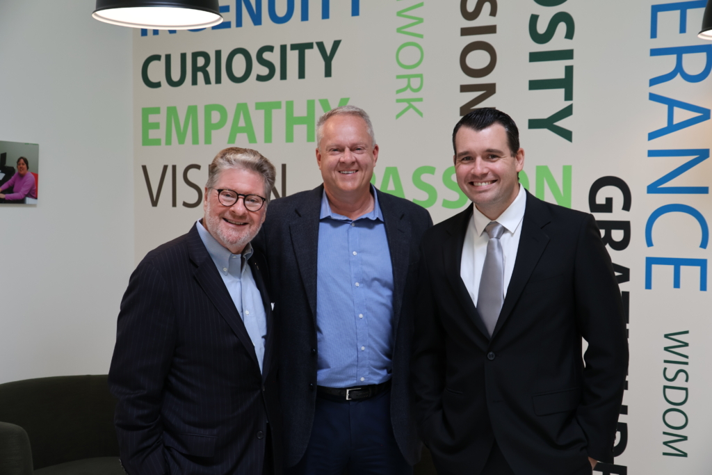 Senator Pete Harckham, Community Engagement Coordinator Joe Conti & David Shepperly of WIN Waste Innovations stand by a mural in the Impact Center for Learning.